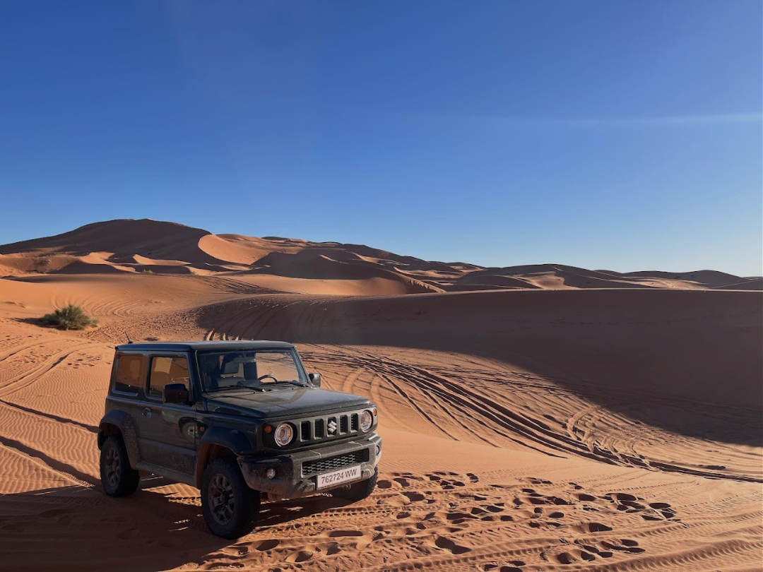 Suzuki Jimny vert olive sur les dunes de sable du désert marocain